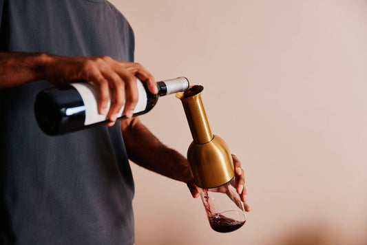 decanting a bottle of red wine into an eto wine decanter in brass satin