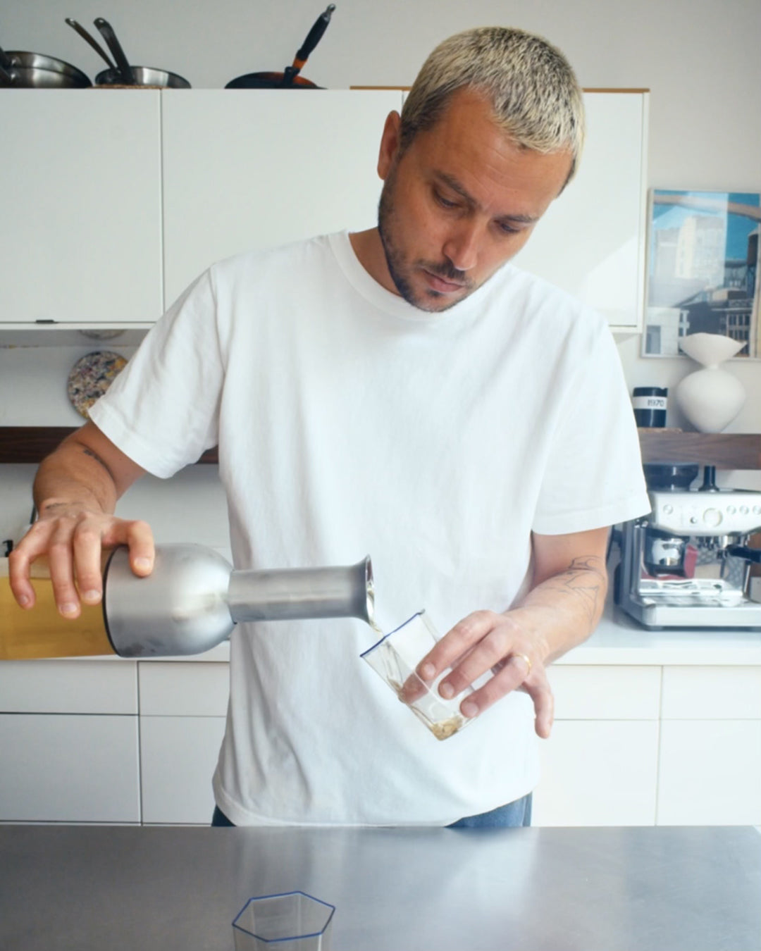 Chef Jessie Jenkins in his kitchen pouring white wine from a stainless satin ETO wine decanter into a glass.