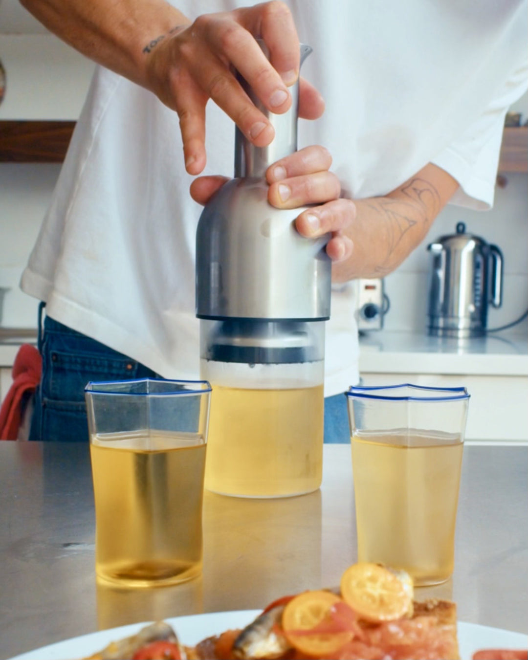 Chef Jessie Jenkins using an ETO stainless satin wine decanter to preserve white wine on a stainless steel kitchen surface.