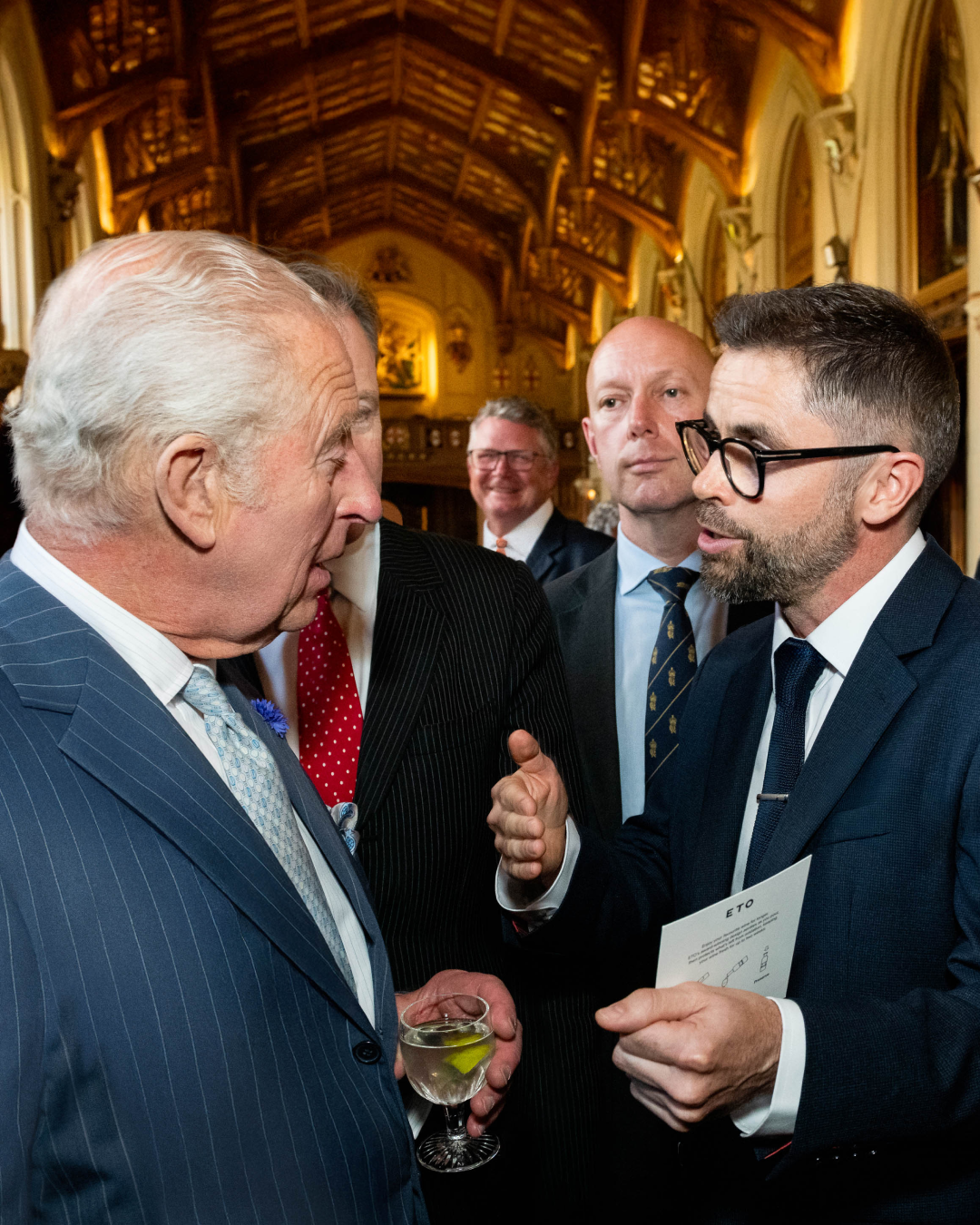 ETO designer Tom Cotton meeting King Charles the third in a grand hall with high ceilings and ornate decorations.