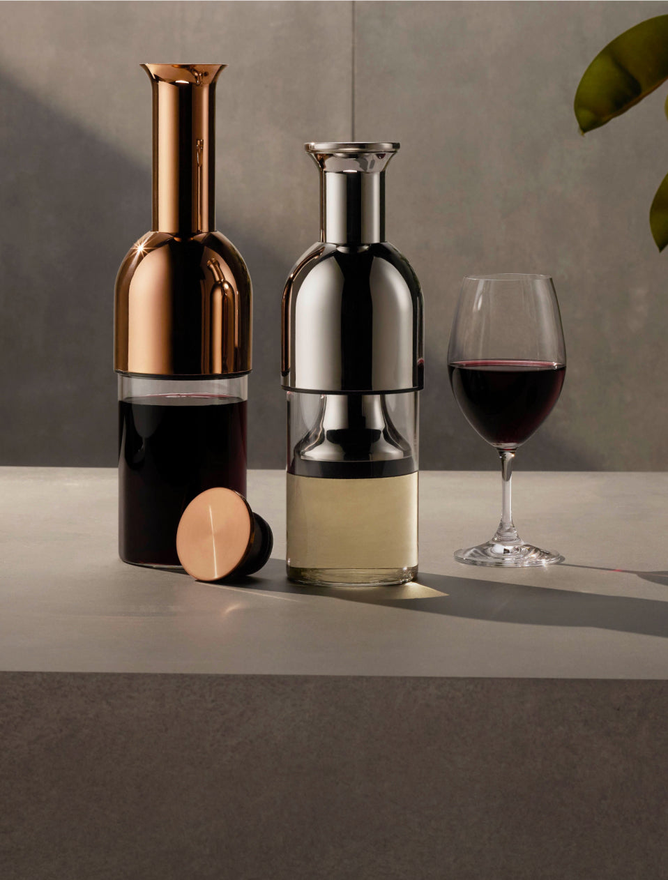 A copper mirror and silver mirror eto side by side with a glass of red wine beside them
