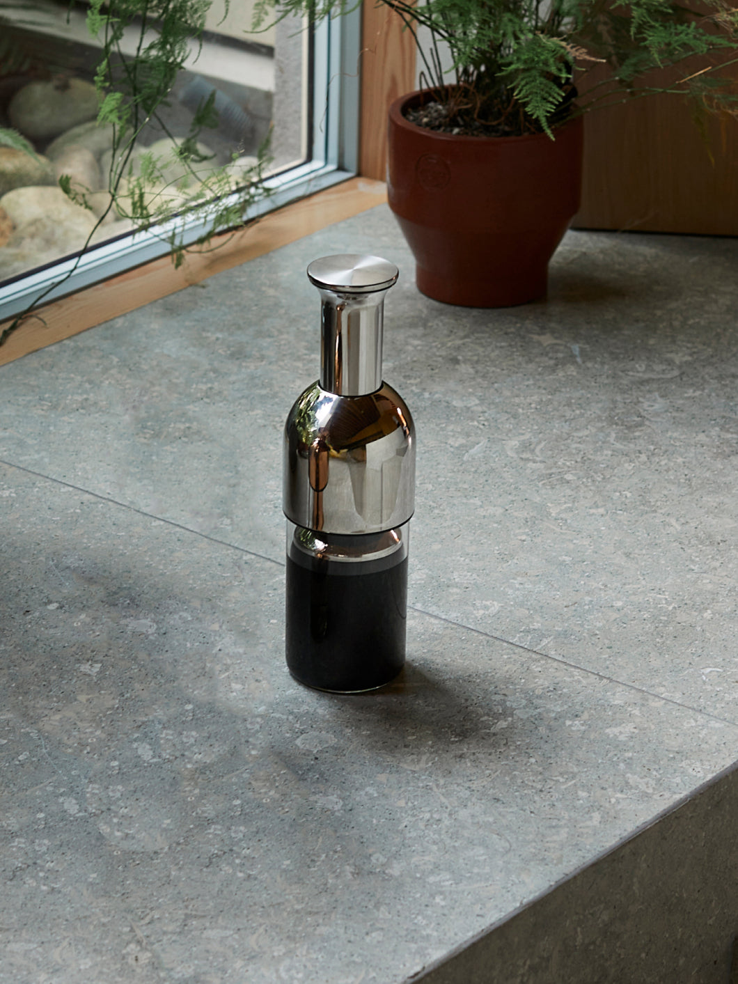 a stainless mirror eto wine decanter on a polished concrete floor