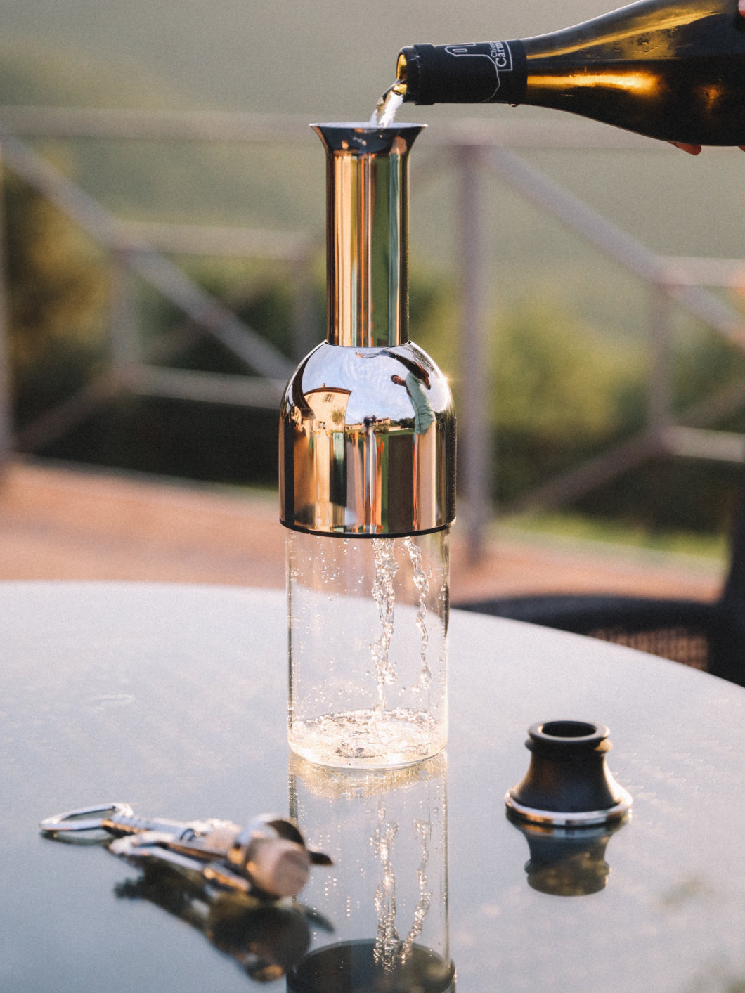 a bottle of white wine being poured into a stainless mirror eto wine decanter