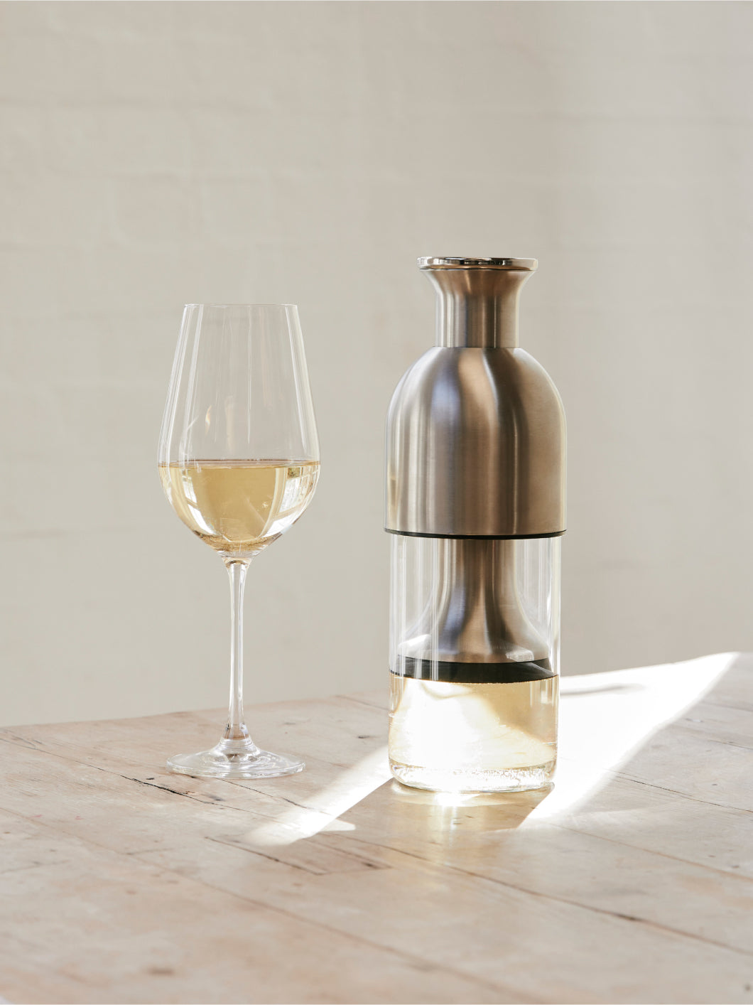 A stainless satin eto decanter beside a glass of white wine