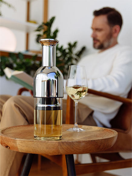eto wine decanter in stainless steel with white wine on top of a side table