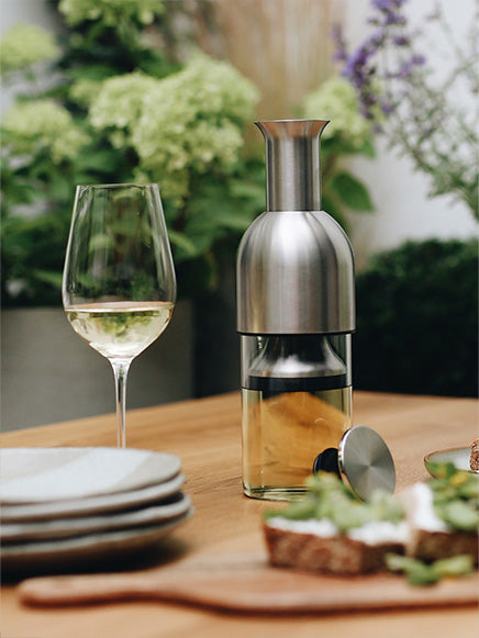 eto wine decanter in stainless steel satin finish on top of an outdoor dining table filled with white wine in the garden